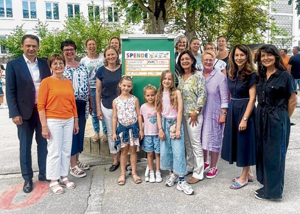Gruppenfoto von Erwachsenen und Kindern bei einer Spendenübergabe im Freien.